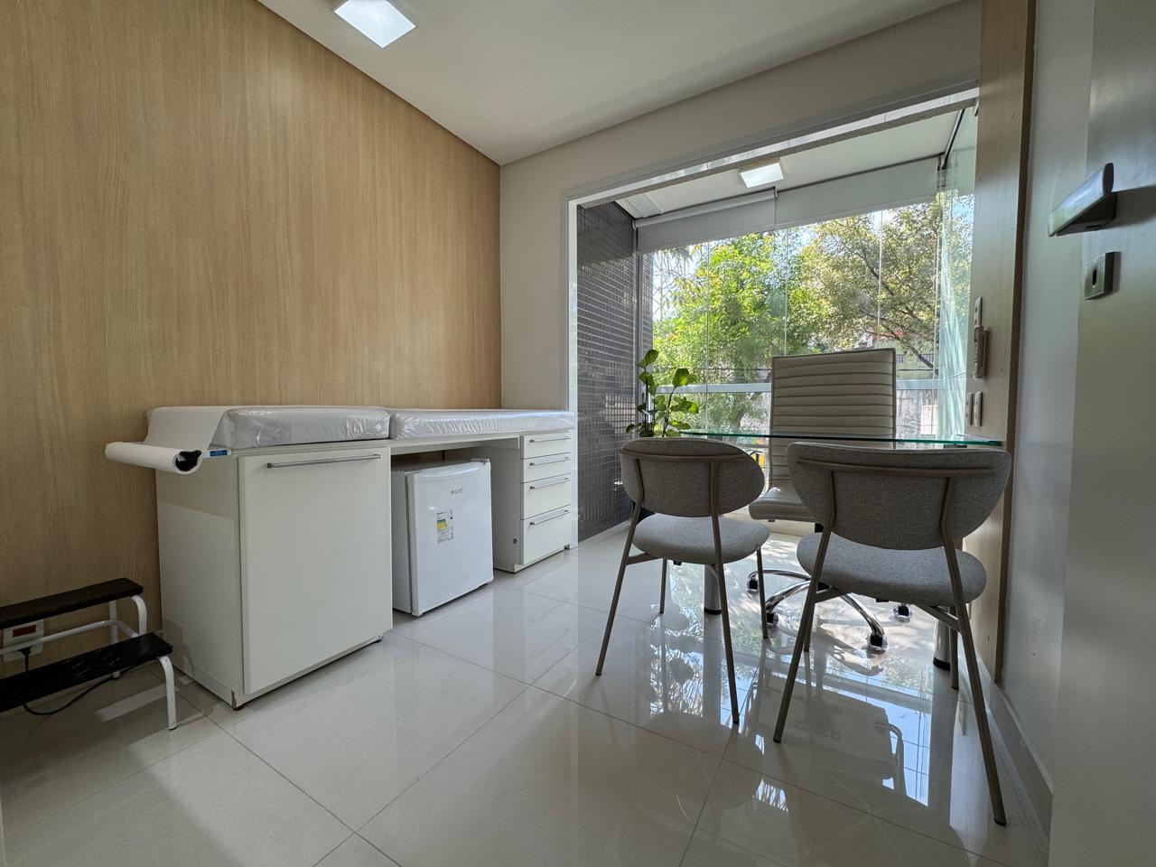 Sala de consulta do Espaço Integer com maca clínica, mesa, cadeiras, pia de apoio e luz natural
