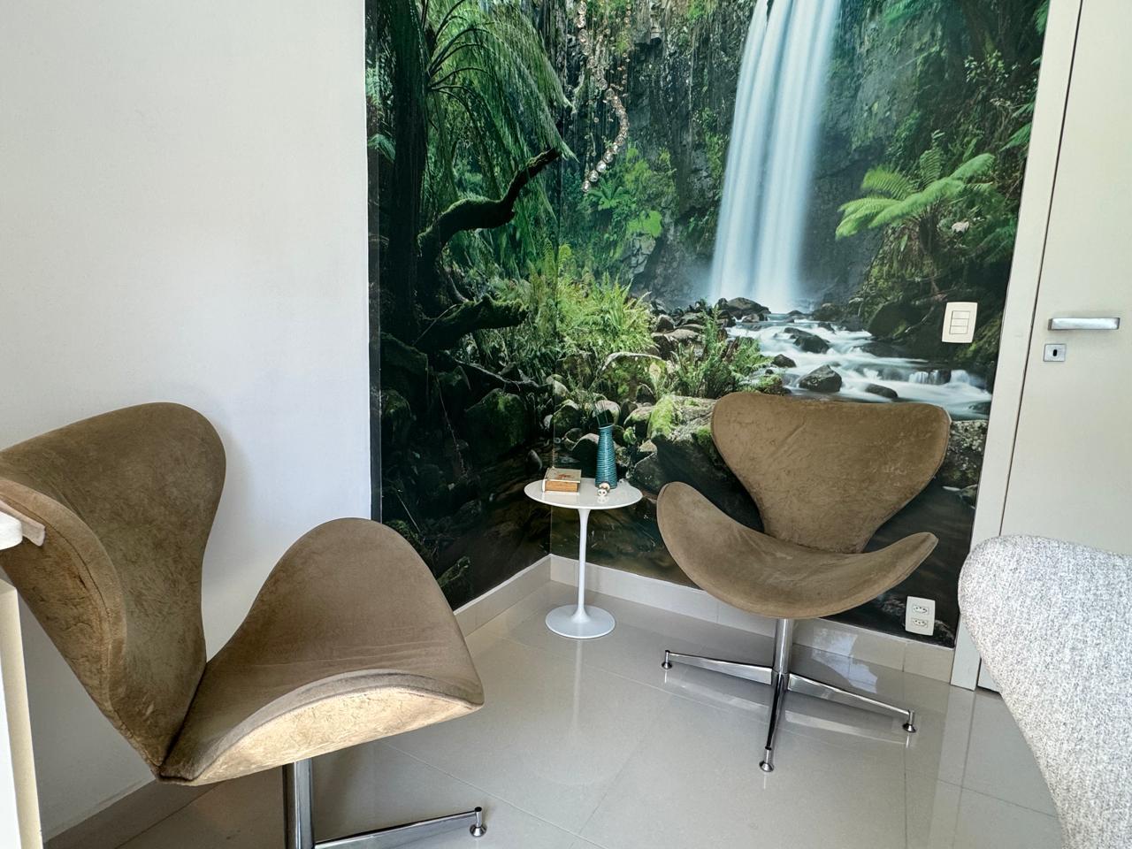 Sala de atendimento do Espaço Integer com poltronas, mesa de apoio, luz natural e vista para o verde